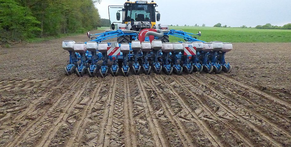 Traktor mit Aussaatgerät fährt auf Feld