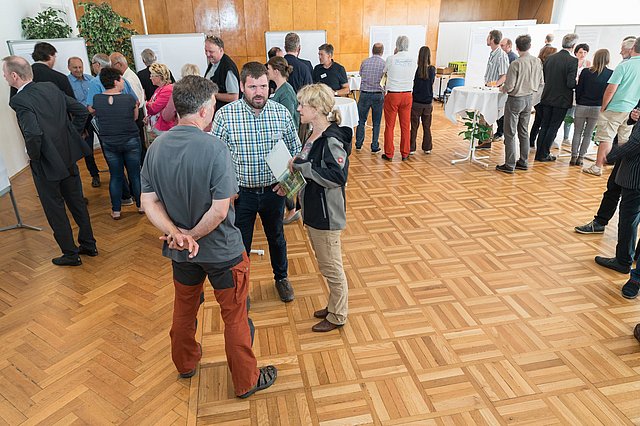 Personen unterhalten sich in Kleingruppen stehend.