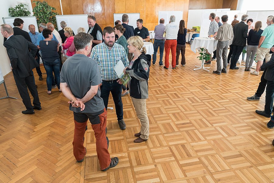 Personen unterhalten sich in Kleingruppen stehend.